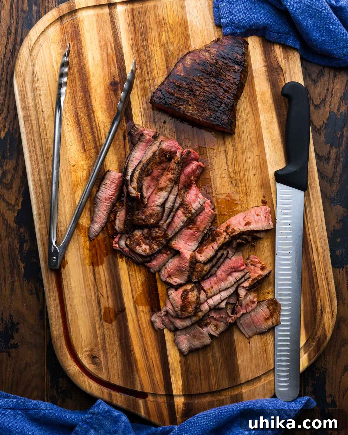 3-Ingredient Magic Marinade for Tender London Broil 2 Sliced Marinated London Broil on a wooden cutting board with a knife and tongs, ready to serve.