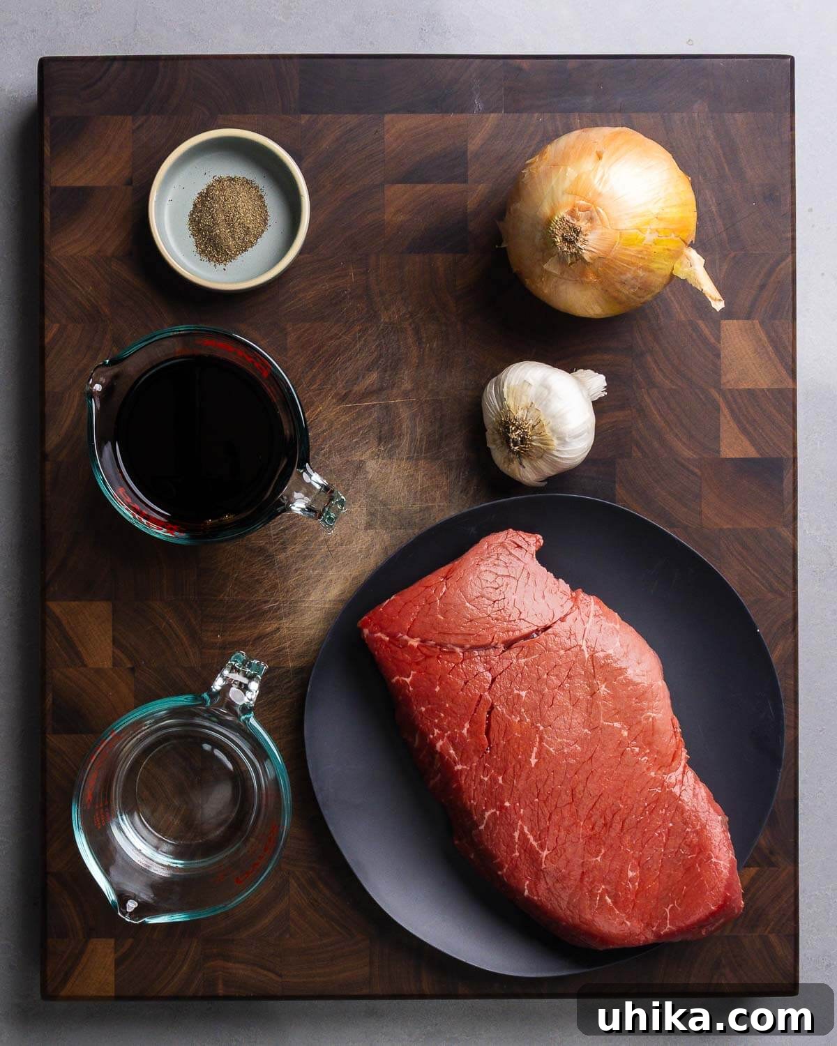 3-Ingredient Magic Marinade for Tender London Broil 4 Ingredients for Marinated London Broil: whole black pepper, quartered onion, whole garlic cloves, light soy sauce, water, and a raw London Broil steak.