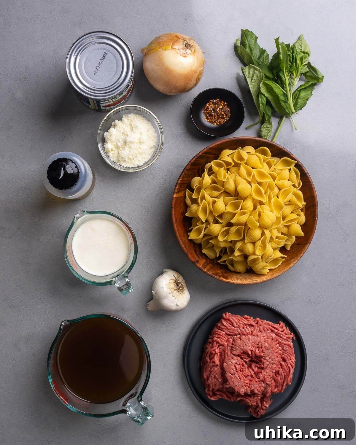 Creamy Beef and Shells Skillet Dinner 4 Ingredients for Creamy Beef and Shells including ground chuck, shell pasta, beef stock, heavy cream, canned plum tomatoes, onion, garlic, red pepper flakes, Pecorino Romano, and fresh basil.