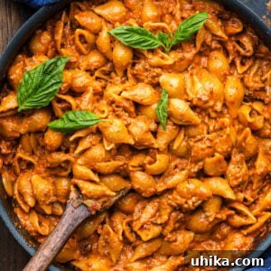 Creamy beef and shells pasta in large black pan with basil garnish, serving suggestion.