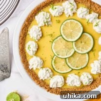 Florida's Zesty Key Lime Masterpiece 7 Creamy Florida key lime pie filling in a white pie plate on a marble background, topped with thin lime slices, lime zest and dollops of whipped cream.