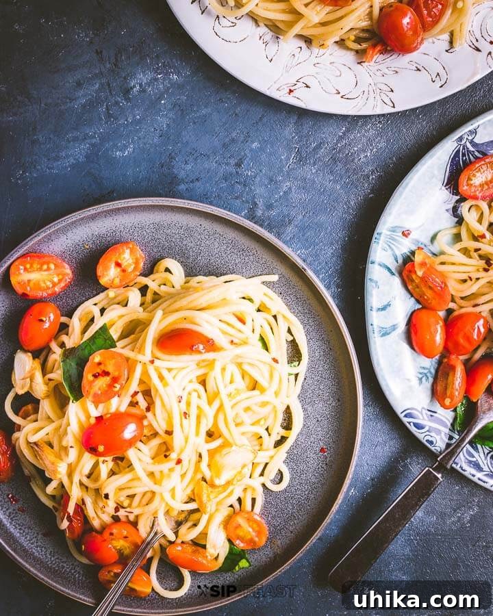 Three plates of spaghetti and cherry tomatoes with basil on a blue background, ready to be served.