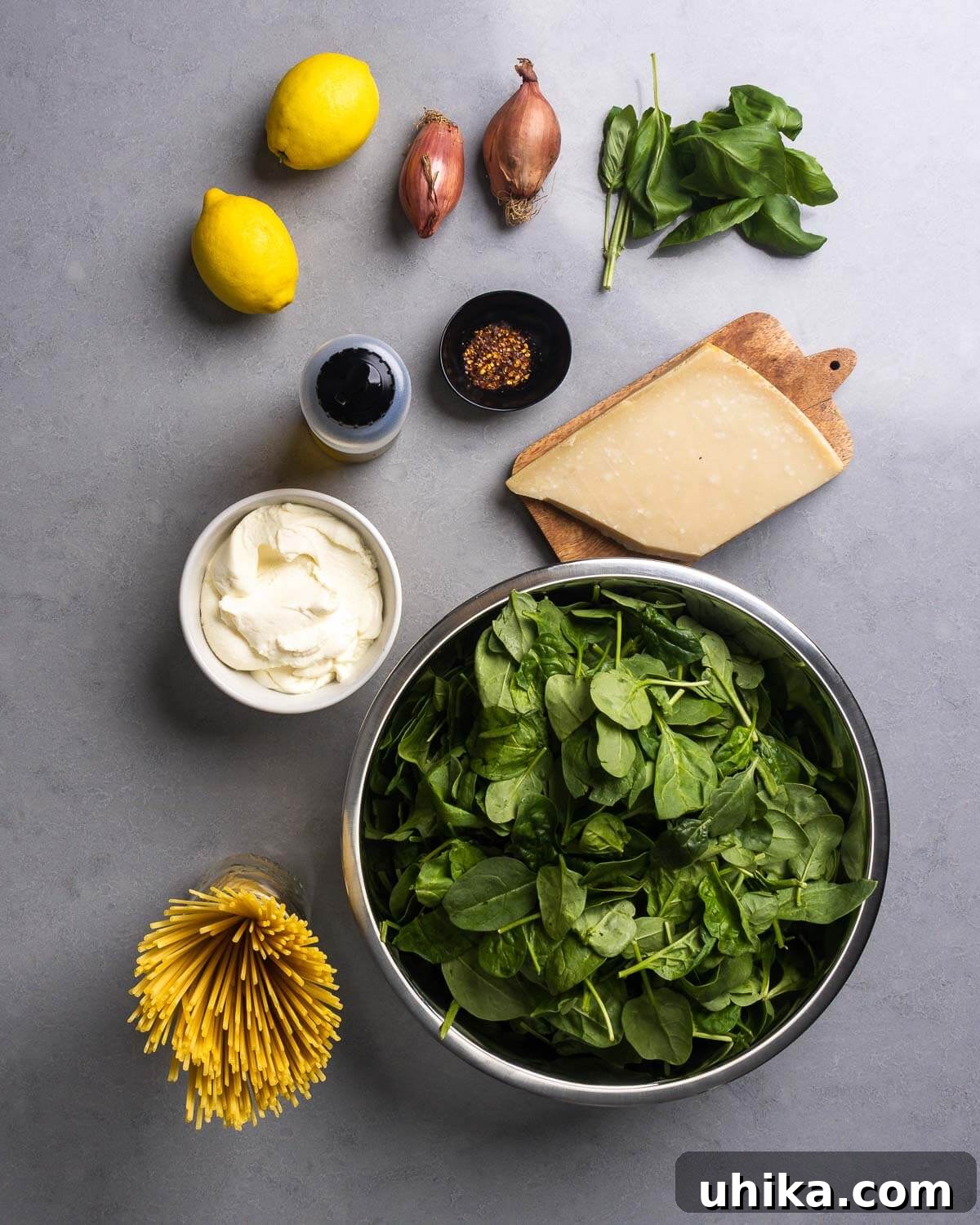 Zesty Lemon Ricotta Spinach Pasta 4 A flat lay photograph showcasing the fresh ingredients: lemons, shallots, basil, olive oil, chili flakes, a block of Parmigiano Reggiano, creamy ricotta, linguine pasta, and fresh baby spinach.
