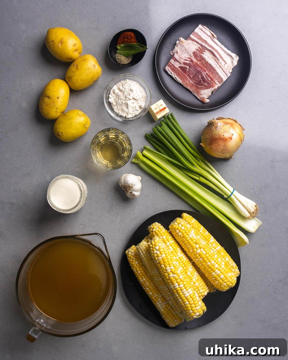 Creamy Golden Corn Chowder 4 A flat lay of all ingredients for corn chowder: potatoes, herbs and spices, bacon, flour, butter, green onions, onion, white wine, garlic, celery, cream, chicken stock, and corn.
