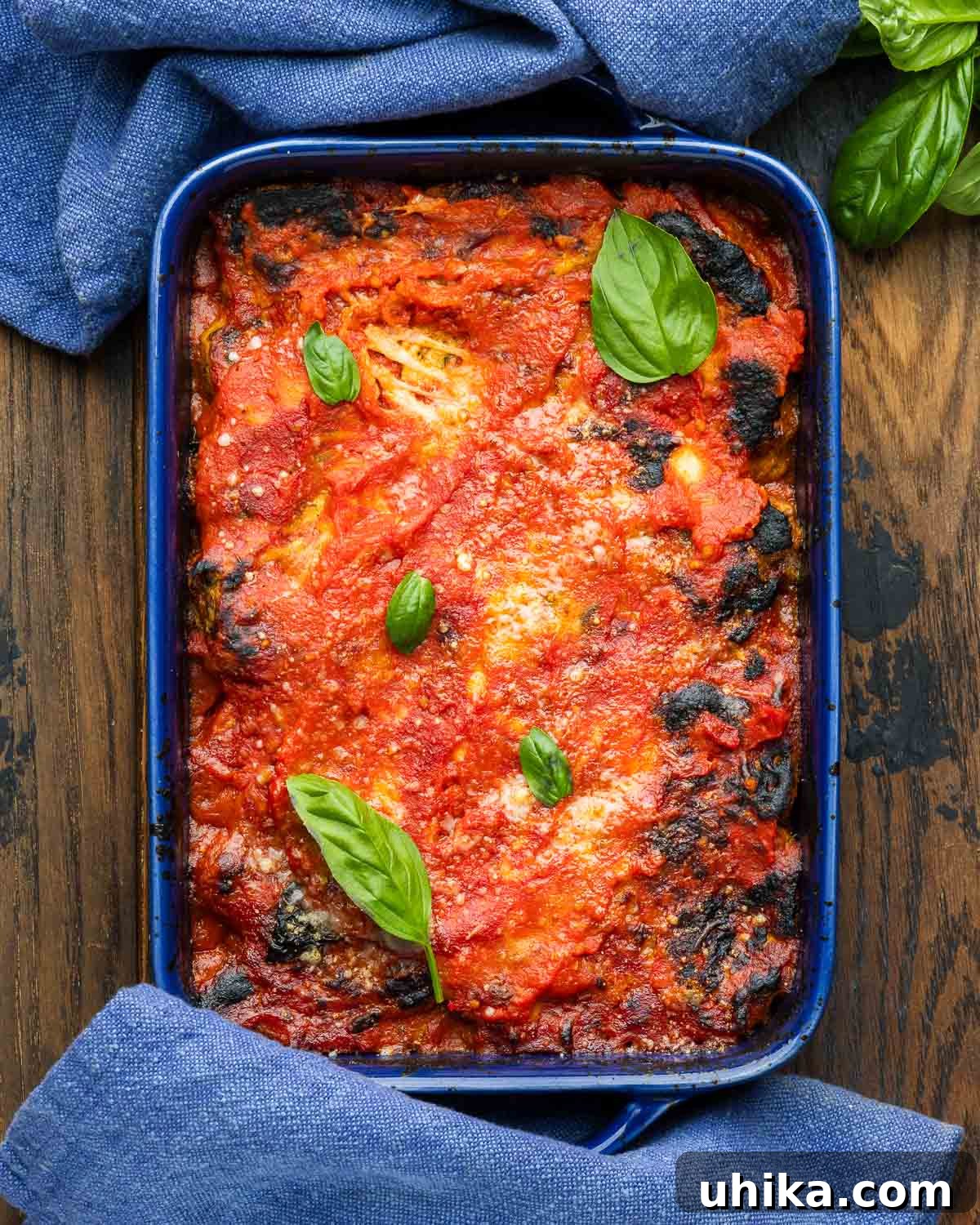 Golden Artichoke Parmesan Bake 2 A vibrant blue baking dish showcasing golden-brown Artichoke Parmesan, bubbling with melted cheese and rich tomato sauce.