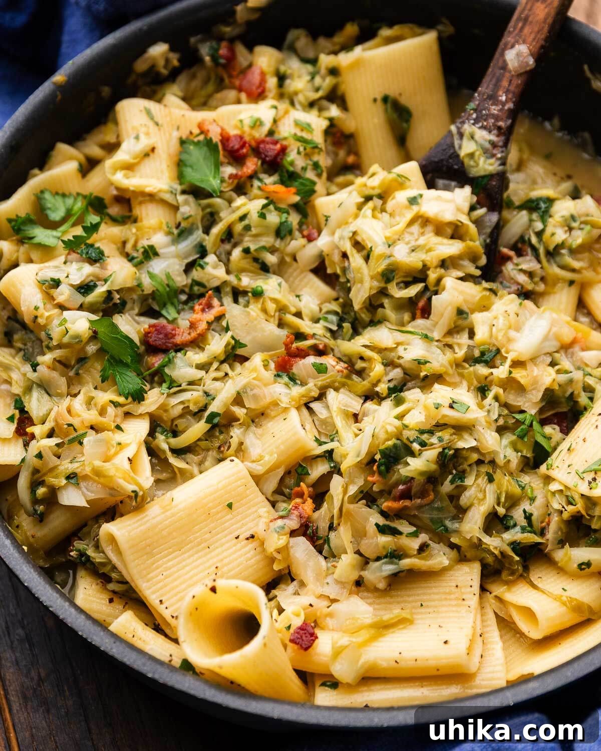 A large pan filled with golden Cabbage Bacon Pasta, garnished with fresh parsley and extra cheese.