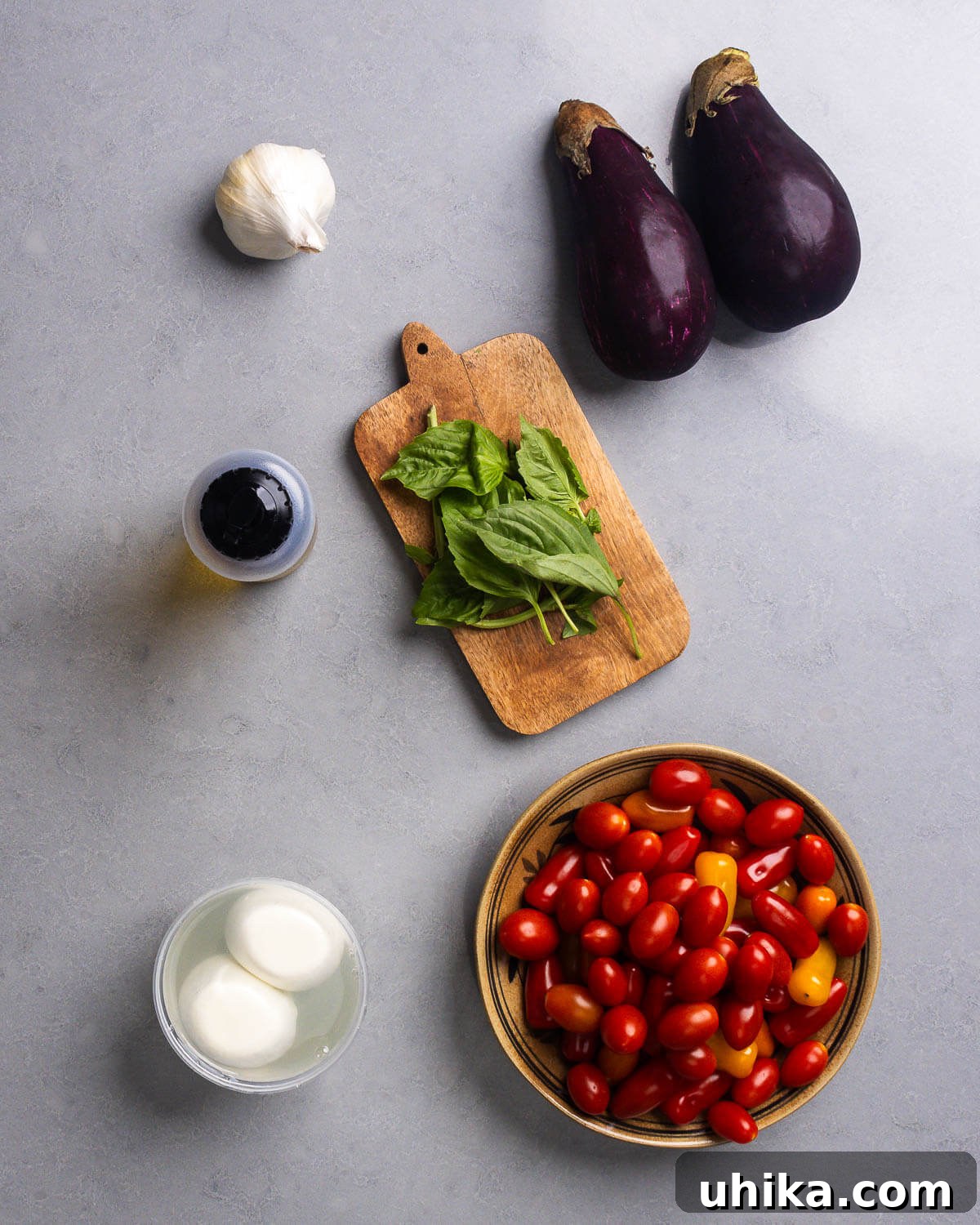 Creamy Burrata with Roasted Eggplant and Sweet Cherry Tomatoes 4 Ingredients shown: garlic, eggplant, olive oil, basil, burrata, and cherry/grape tomatoes.