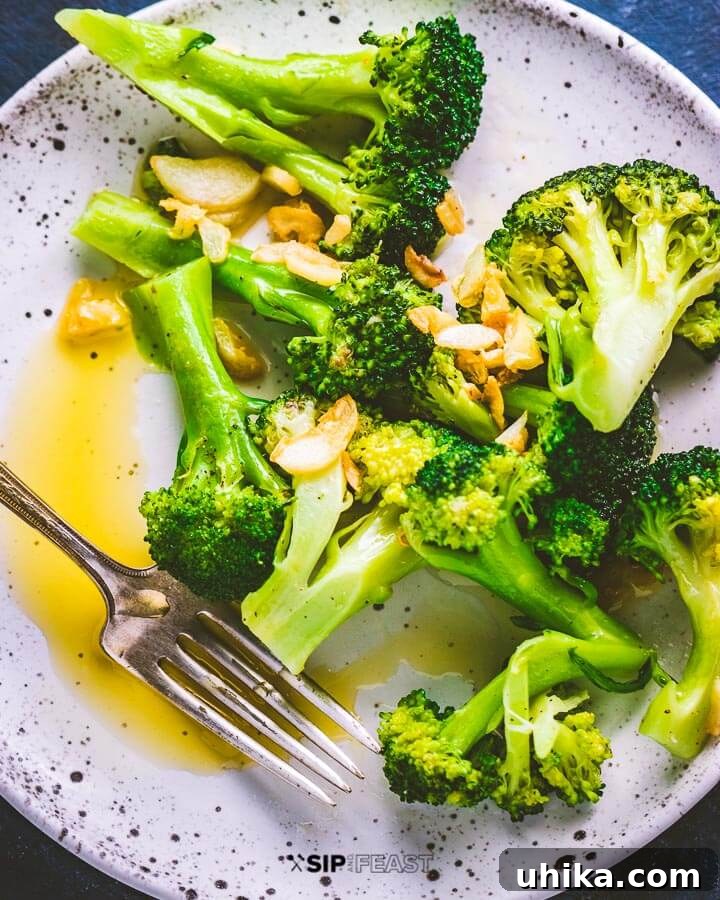 Classic Italian Broccoli with Garlic and Olive Oil - A simple and healthy side dish for any meal. #italianbroccoli #garlicbroccoli #sidedish #healthyrecipe A serving of Italian broccoli with garlic and olive oil on a white plate, ready to be enjoyed with a fork.
