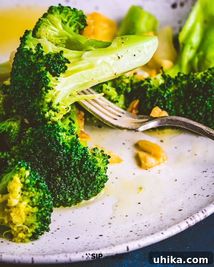 Perfectly Cooked Broccoli Florette - A bite-sized piece of healthy deliciousness. #broccoli #healthyfood Close-up shot of a single broccoli floret, perfectly cooked and held by a fork.