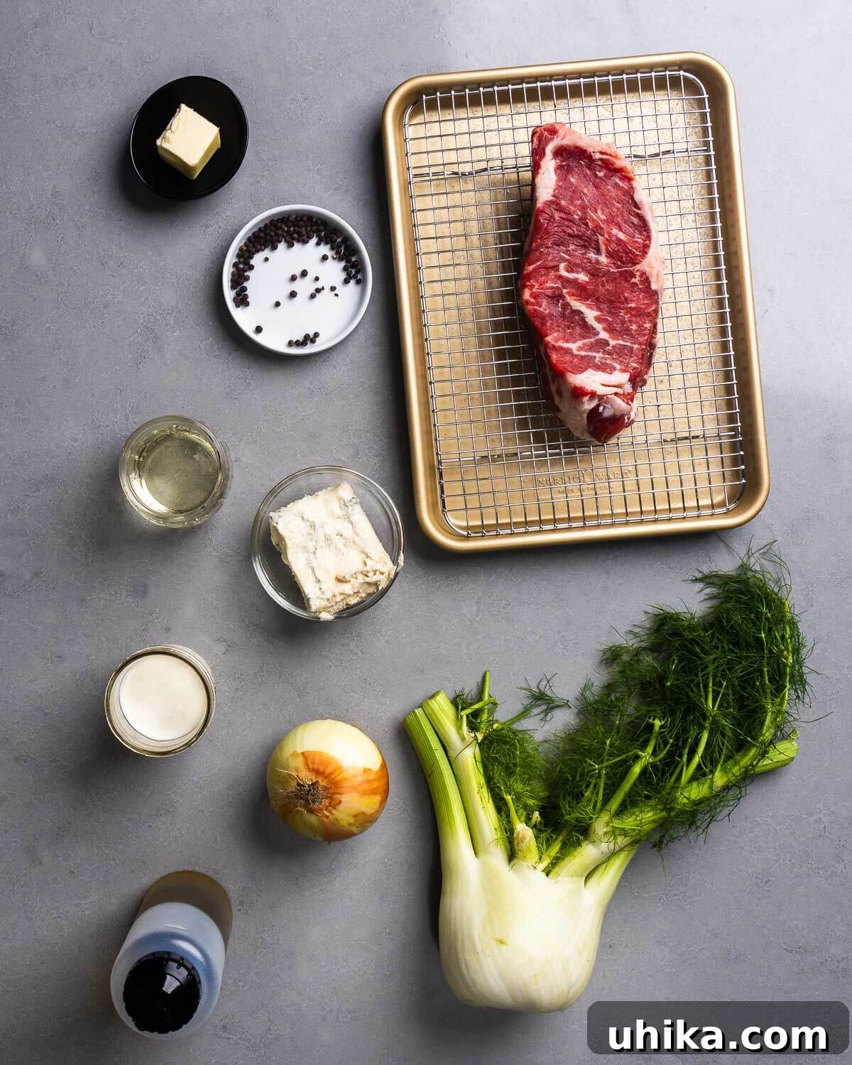 A vibrant flat lay image showcasing all the fresh ingredients for the NY strip steak with gorgonzola sauce: butter, whole black peppercorns, raw New York strip steak, a bottle of dry white wine, a wedge of gorgonzola cheese, heavy cream, a white onion, olive oil, and a fresh fennel bulb.