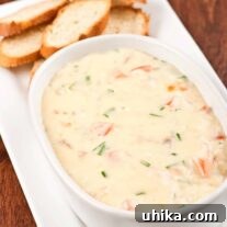Smoked fish and Dubliner cheese dip in a serving bowl alongside toasted baguette rounds.