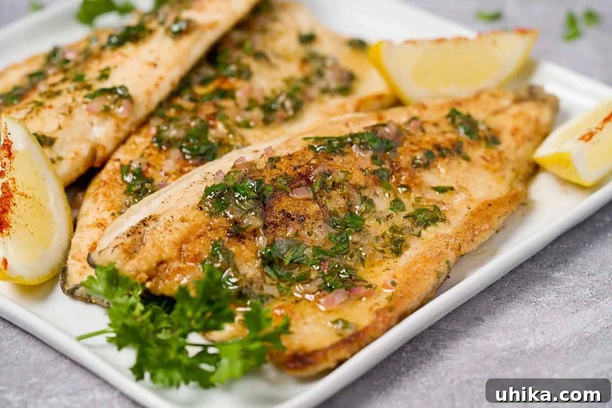 Quick and Easy Lemon Butter Trout 4 A close up of rainbow trout meunière showing a drizzle of lemon-parsley brown butter sauce. The plate is garnished with fresh lemon wedges and sprigs of parsley.