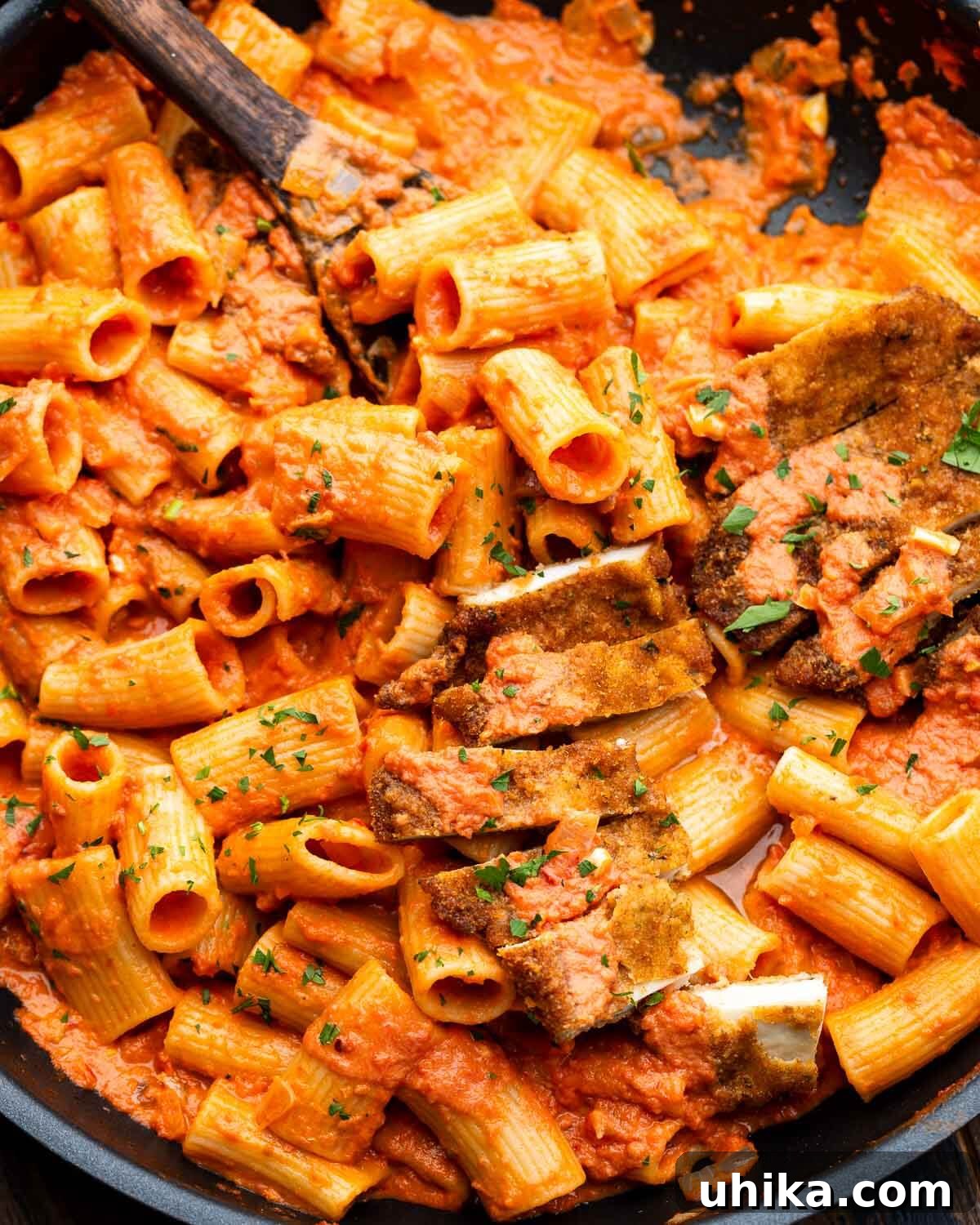 Crispy Chicken Cutlets with Fiery Vodka Rigatoni 2 Large pan with spicy vodka rigatoni and sliced chicken cutlets, garnished with fresh parsley.