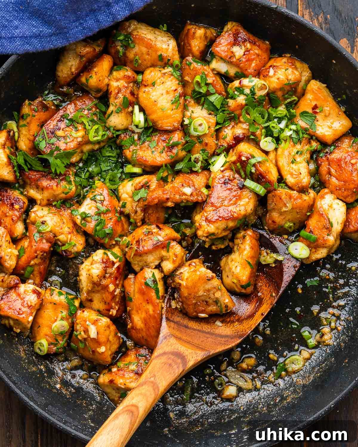 Buttery Garlic Chicken Poppers 2 Golden-brown garlic butter chicken bites resting in a black pan, garnished with fresh herbs.