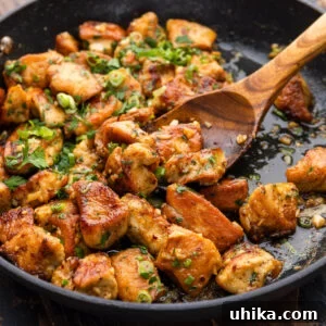 Garlic butter chicken bites scooped with a wooden spoon, ready to be served.