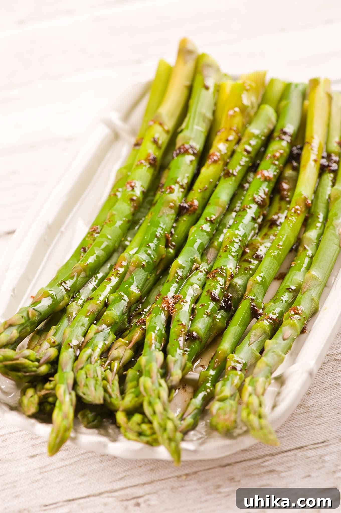 A platter of exquisitely steamed asparagus spears, elegantly drizzled with a rich balsamic brown butter sauce. This gourmet side dish is perfect for enhancing any meal.