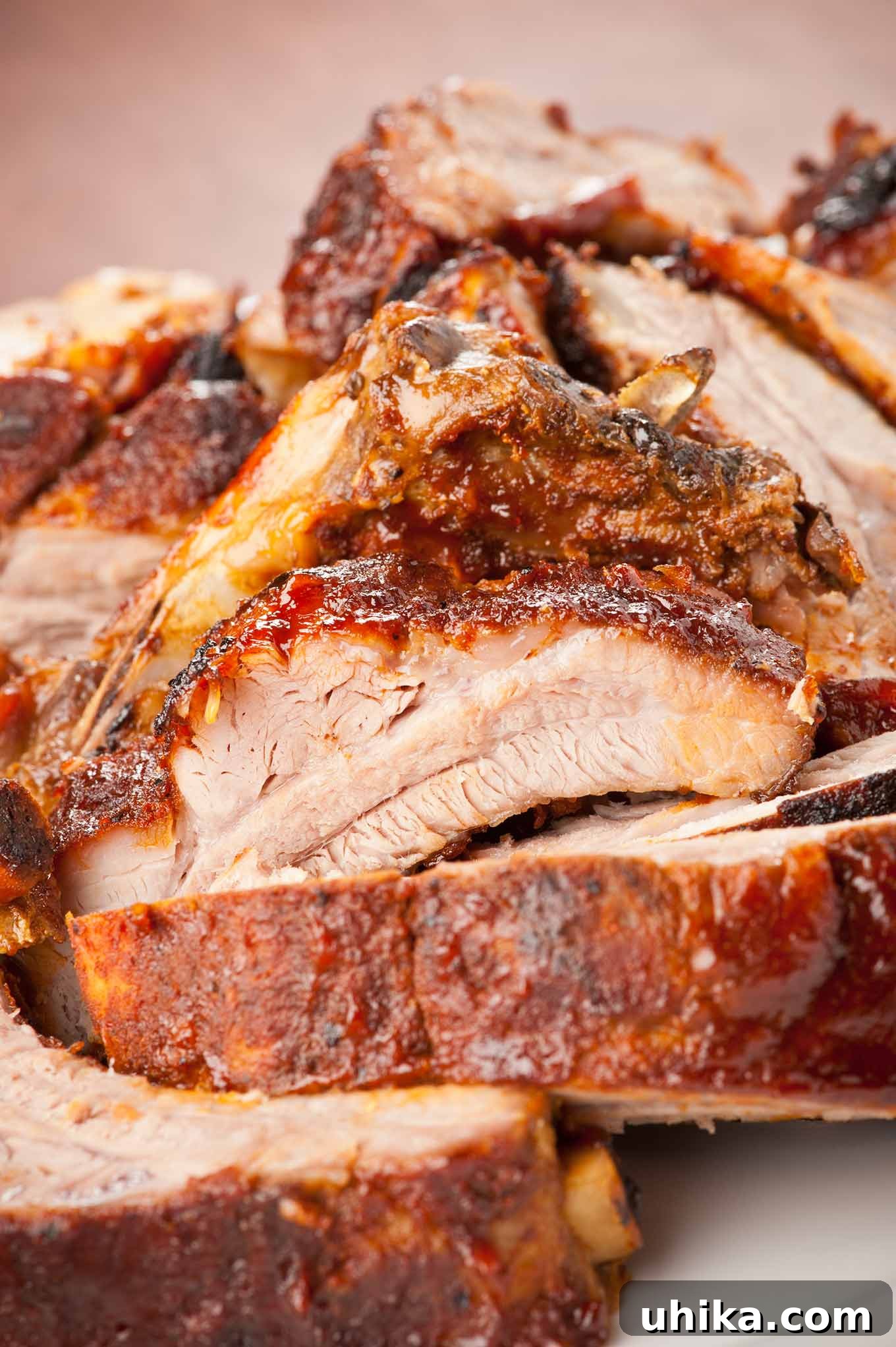 Fall-Off-The-Bone Oven Ribs 3 A close, side view of a platter of cut up oven baked baby back ribs showing the moist, tender texture of the meat.