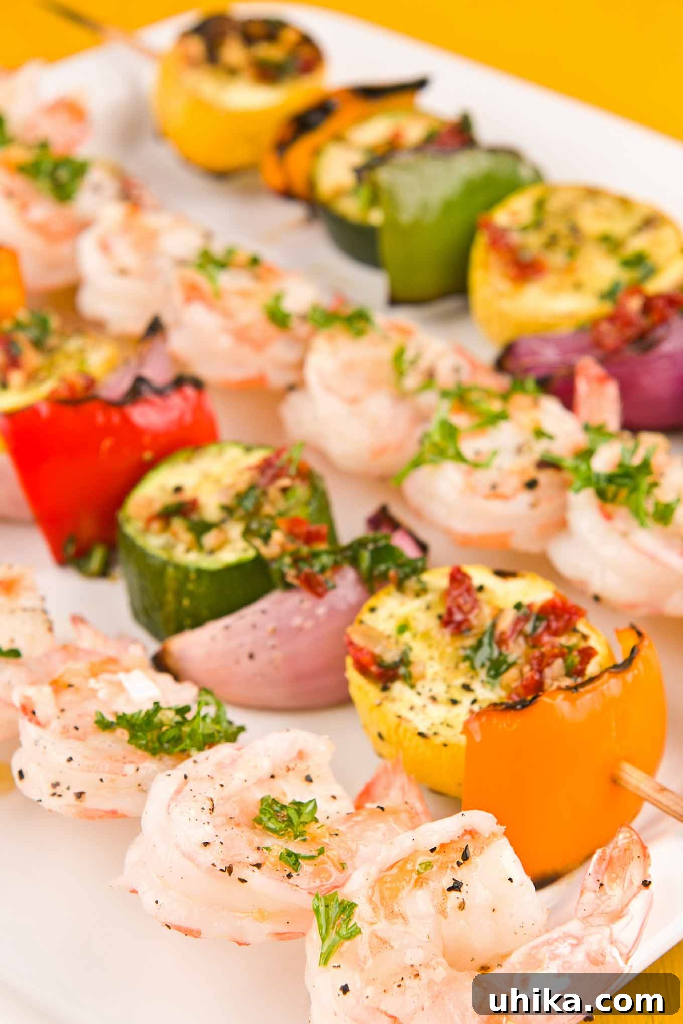 Close-up view of freshly grilled shrimp and vegetable skewers, beautifully garnished with chopped parsley and presented on a serving plate.