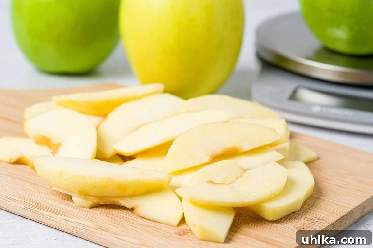 Heartwarming Apple Betty Bake 4 Thinly sliced apples prepared on a cutting board, surrounded by whole apples and a kitchen scale, ready for the Apple Brown Betty recipe.