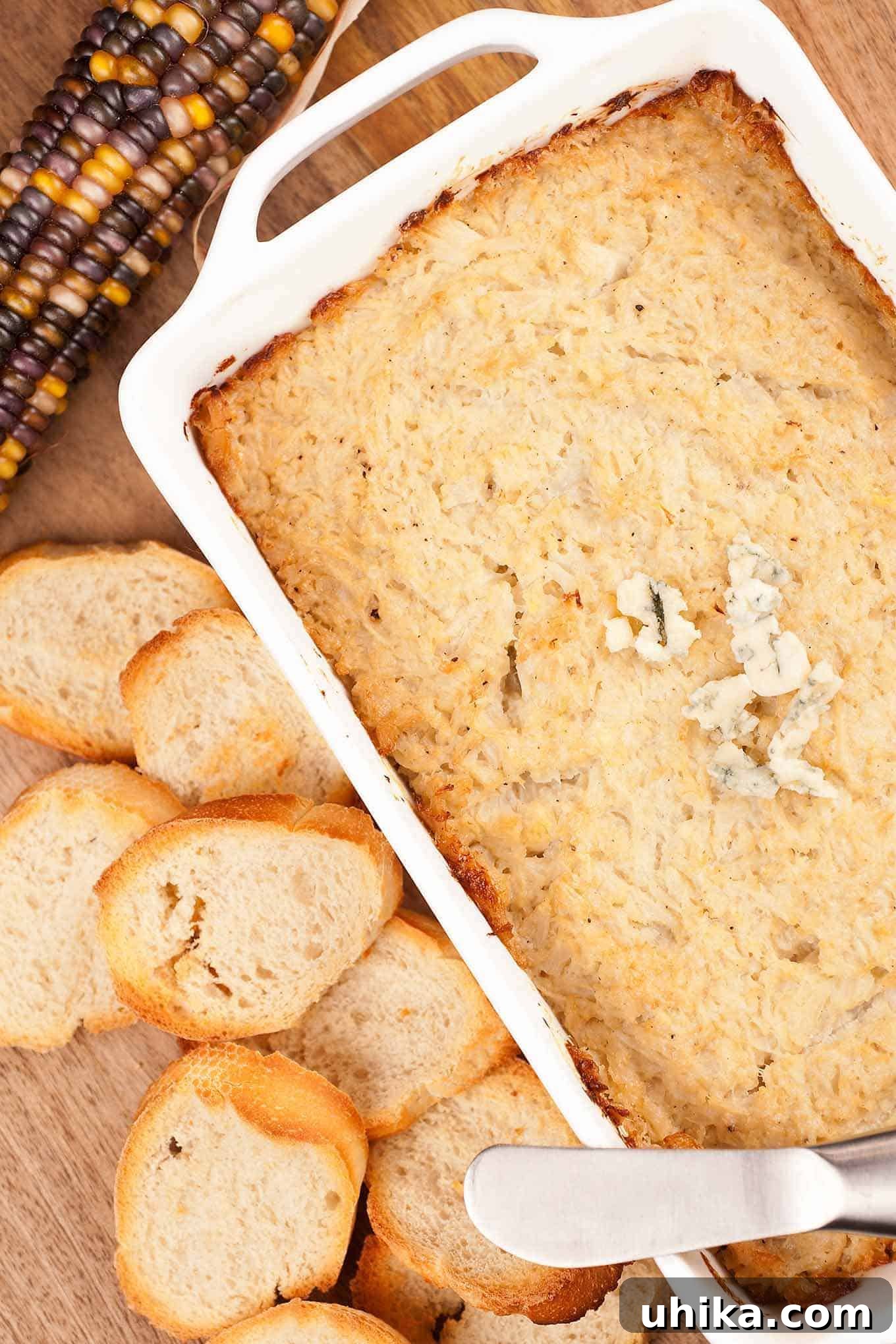 Whipped Cauliflower Blue Cheese Dip 2 Creamy baked cauliflower and blue cheese dip in a white oblong casserole with toasted baguette slices on the side, ready for entertaining.