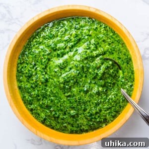 Italian salsa verde in wooden bowl on white granite.