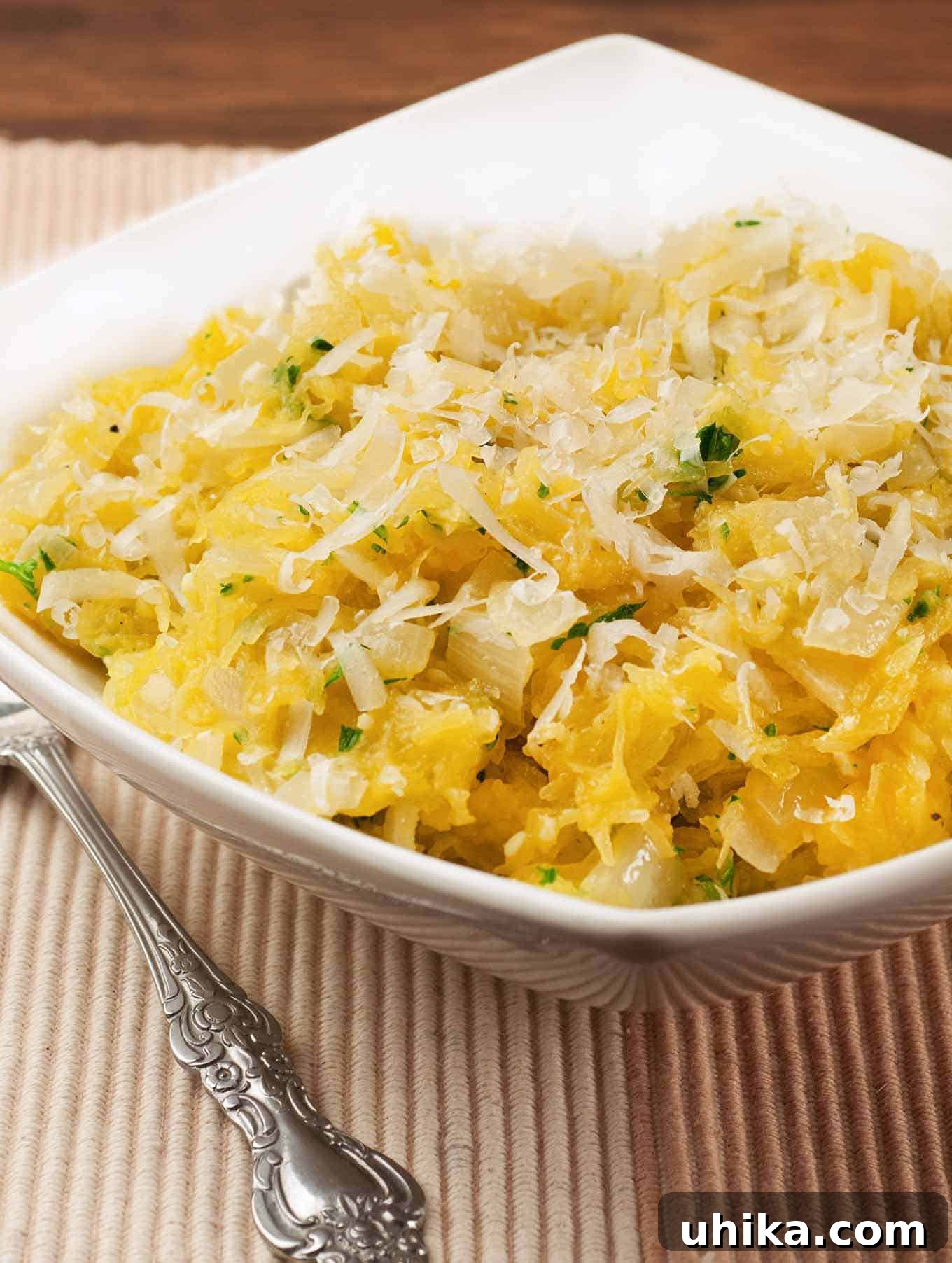 Savory Garlic Parmesan Spaghetti Squash 2 Delicious Garlic Parmesan Spaghetti Squash in a white bowl, mixed with sautéed onion, garlic, and fresh herbs, topped with grated cheese. A healthy and low-carb side dish alternative.