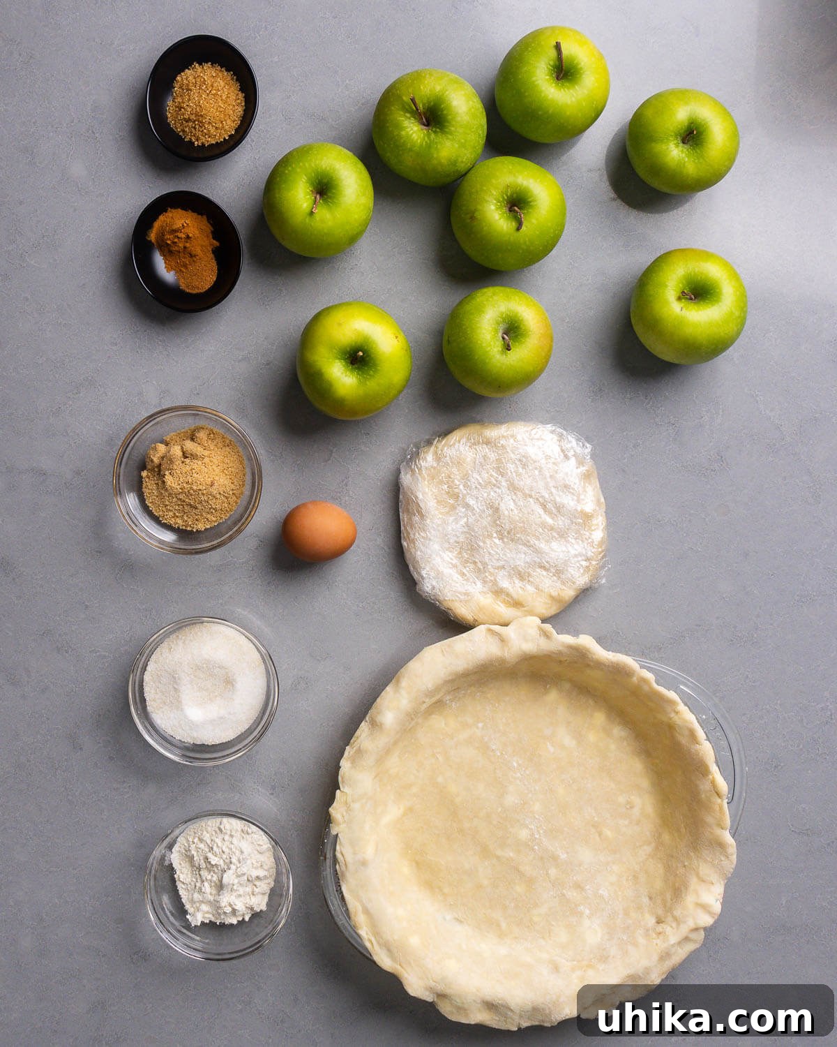Timeless Flaky Apple Pie 5 Apple pie ingredients shown: turbinado sugar, cinnamon, nutmeg, Granny Smith apples, egg, chilled pie crusts, brown sugar, sugar, and flour.