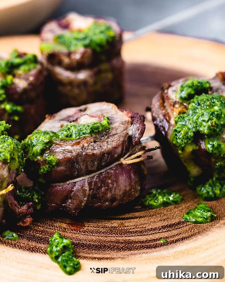 Grilled Flank Steak Pinwheel with Salsa Verde A close-up shot of a perfectly grilled flank steak pinwheel topped with a dollop of vibrant green Italian salsa verde, highlighting its delicious layers.