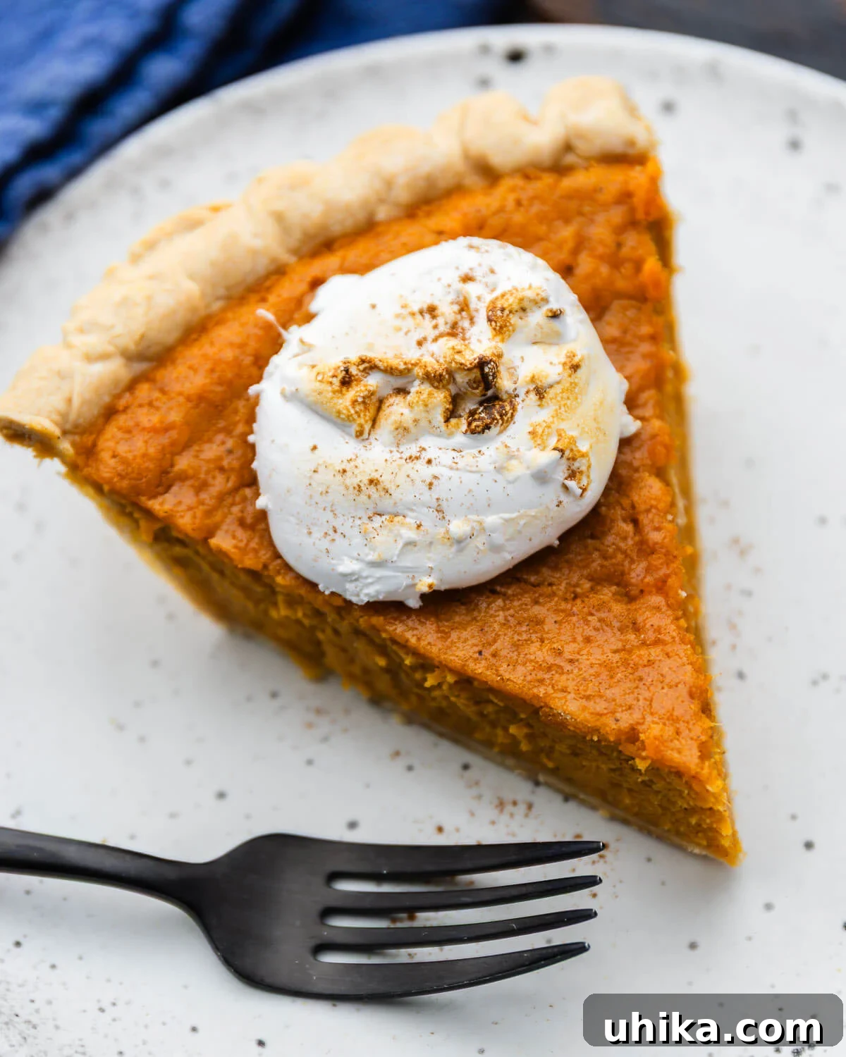 Velvet Sweet Potato Pie 2 Slice of creamy sweet potato pie on a white plate with a fork, ready to be enjoyed.