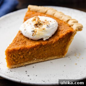 Slice of sweet potato pie with marshmallow topping on white plate.