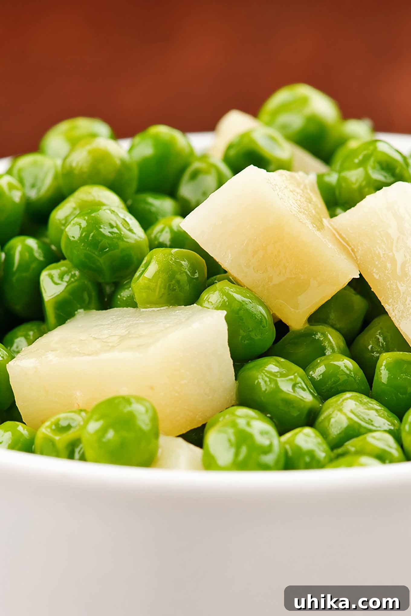 Vibrant Buttered Peas and Parsnips Side Dish A serving dish filled with perfectly buttered green peas and tender chunks of boiled parsnips, glistening with melted butter and ready to be served.
