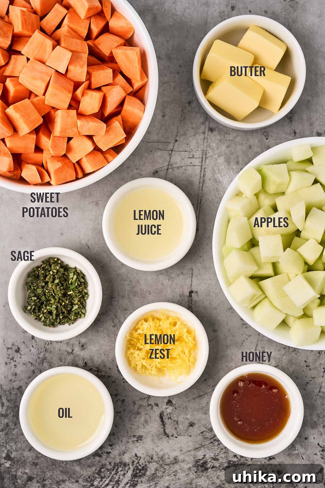 Caramelized Sweet Potato & Apple Gems 3 An overhead, labeled photo of the ingredients for roasted sweet potatoes and apples including butter, lemon juice and zest, honey, fresh sage, and oil.