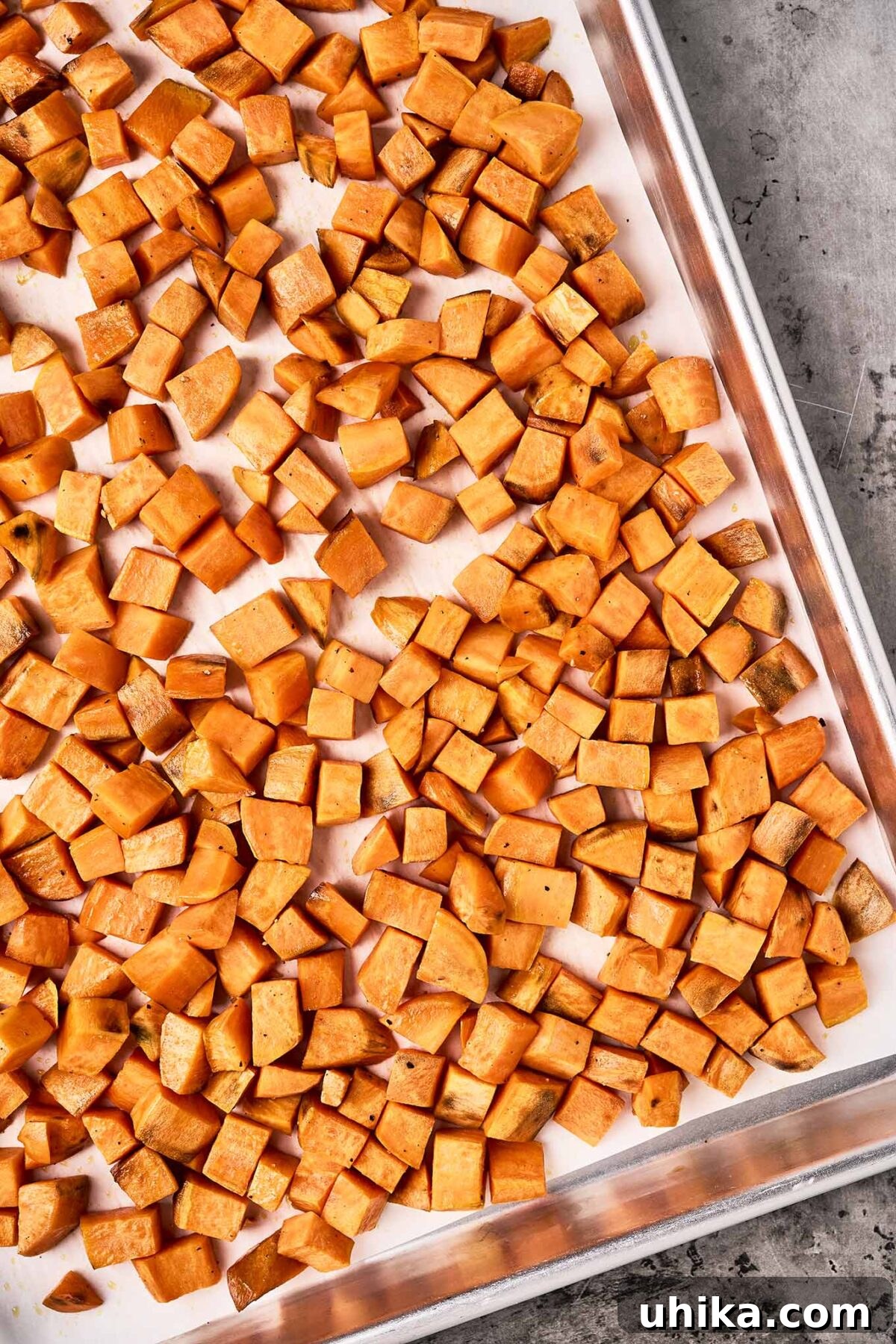 Caramelized Sweet Potato & Apple Gems 4 First step in preparing sweet potatoes and apples - cubes of roasted sweet potatoes on a parchment-lined baking sheet.