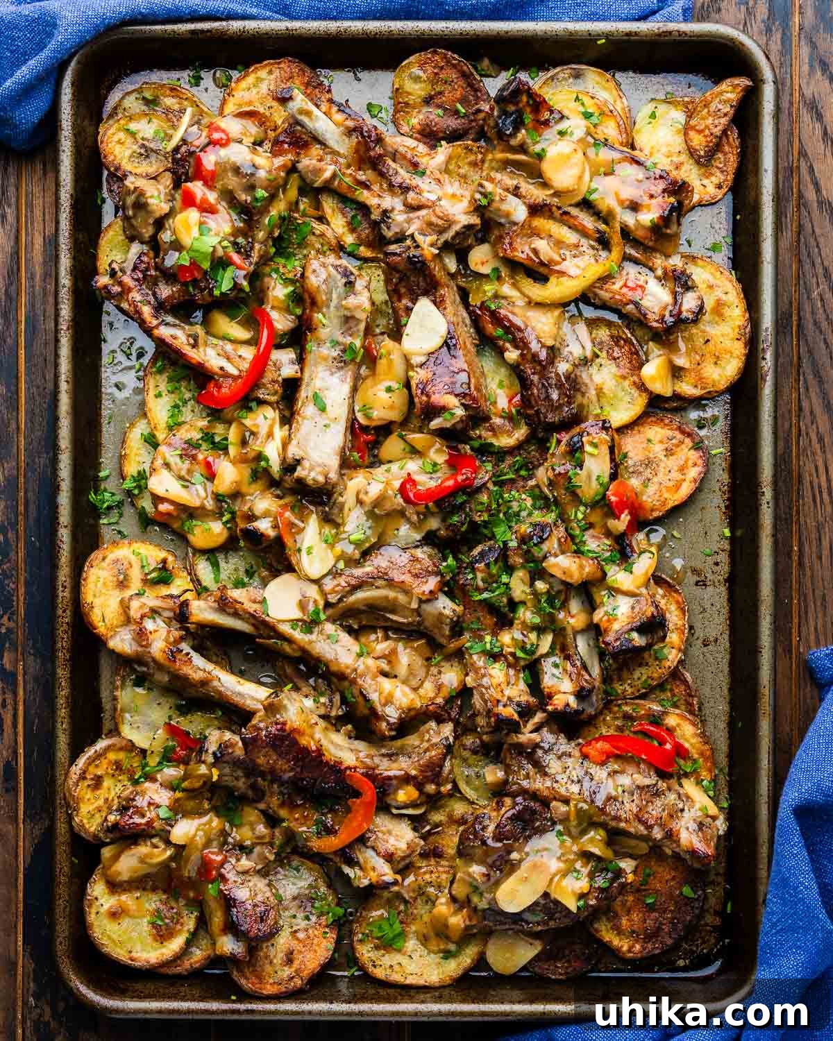 Sweet & Sticky Ribs with Golden Roasted Potatoes 2 Sticky ribs with crispy potatoes in large sheet pan, ready to serve, garnished with fresh herbs.
