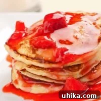 Close-up of fluffy ricotta pancakes with strawberry-orange sauce.