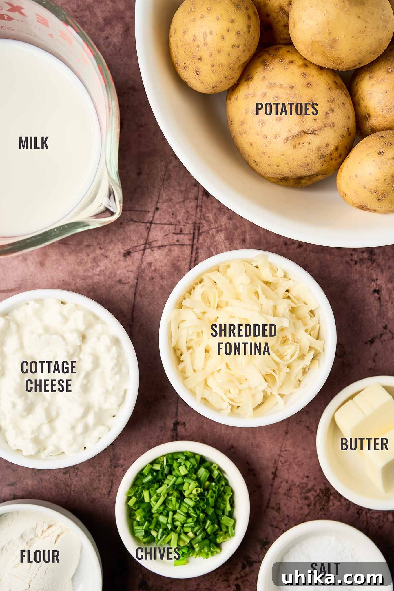 Creamy Cottage Potato Gratin 3 A labeled, overhead view of the ingredients for cottage cheese potato bake, including potatoes, milk, cottage cheese, shredded Fontina, butter, flour, chives, and salt.