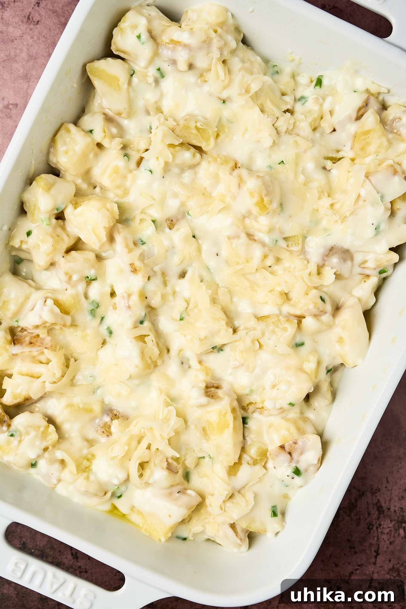 Creamy Cottage Potato Gratin 5 Unbaked cottage cheese potato bake in a white dish, filled with chopped potatoes with creamy cheese sauce and sprinkled with shredded Fontina, ready for the oven.