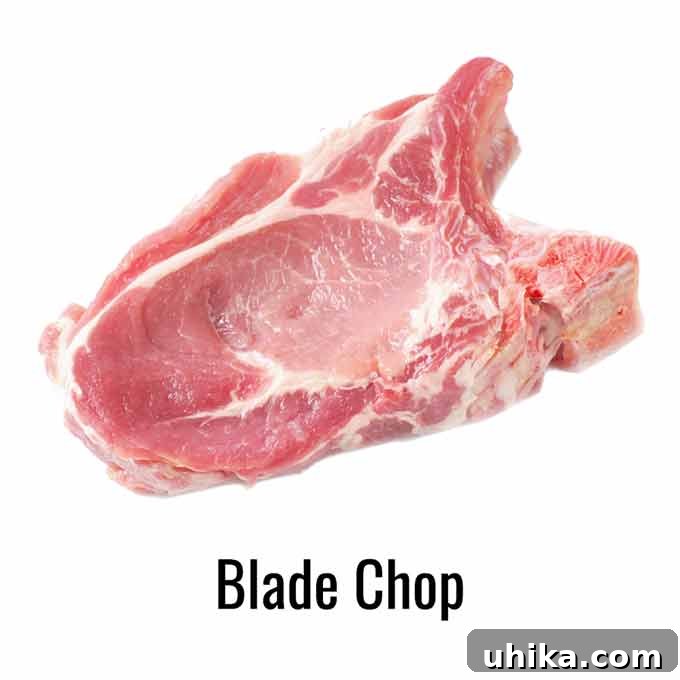Effortless Crispy Oven Pork Chops 5 A raw pork blade chop with visible marbling and connective tissue on a white background.