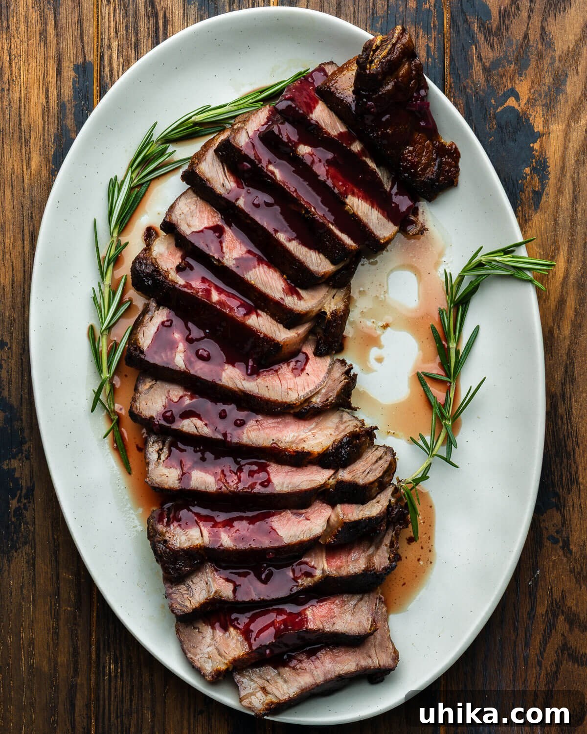 Decadent Ribeye with Red Wine Reduction 2 Platter with sliced ribeye steak drizzled with red wine reduction sauce, ready to serve.