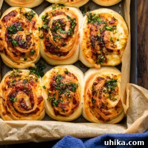 Gooey Garlic Stuffed Cheese Rolls 8 A close-up photograph of freshly baked cheesy garlic rolls in a grey pan, showing the golden-brown crust and melted cheese.