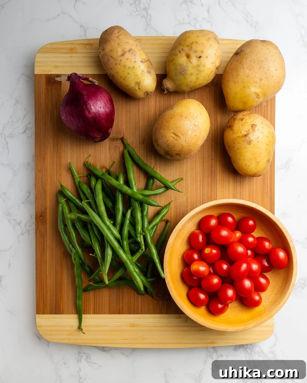 Rustic Italian Potato Salad with Green Beans and Tomatoes 4 Ingredients for Italian Potato Salad displayed: red onion, various types of potatoes, fresh green beans, and vibrant cherry tomatoes.