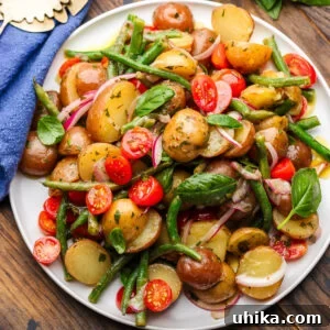 Close-up of vibrant Italian potato green bean salad on a white platter.