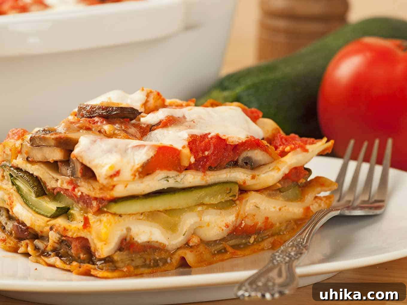 Fresh Garden Lasagna 3 A close-up of a slice of vegetable lasagna with visible layers of pasta, vegetables, and cheese on a white plate.