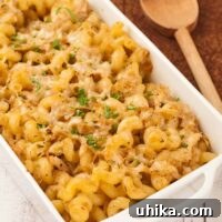 Baked cavatappi pasta with cabbage and thyme in a white casserole dish, topped with melted Parmesan cheese and parsley.