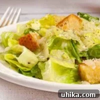 A serving of easy-to-make Caesar salad topped with garlic butter croutons and grated Parmesan cheese.