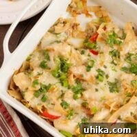 A casserole dish filled with layers of chicken in a creamy cilantro sauce, bell pepper, and pan-fried corn tortilla strips topped with mozzarella and cilantro.