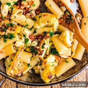 Smoky Bacon & Roasted Cauliflower Rigatoni 2 Rigatoni, cauliflower and bacon in pan on wooden table.