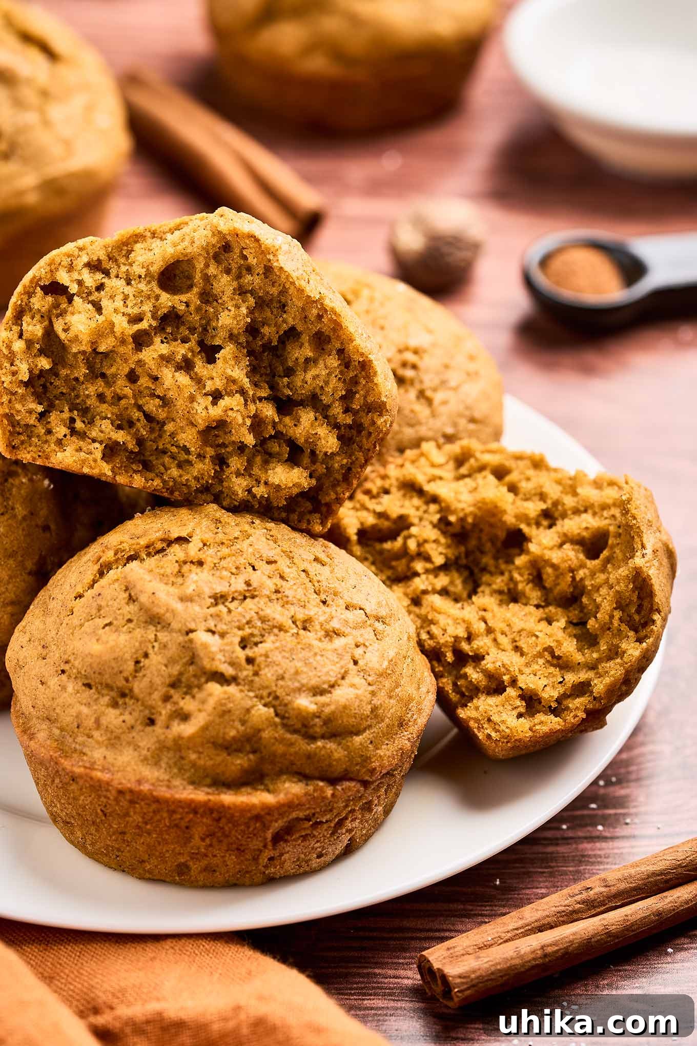 Cozy Pumpkin Spice Bites 7 A plate of moist, airy pumpkin spice muffins with a golden-brown crust and soft, tender crumb on a plate surrounded by spices.