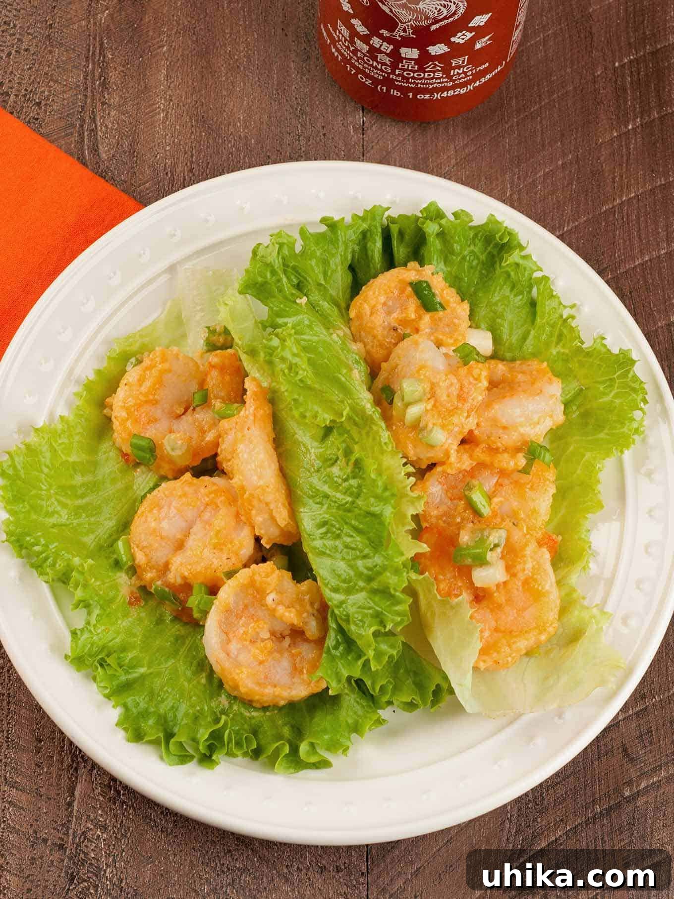 Zesty Bang Bang Shrimp Lettuce Cups 2 Bang Bang shrimp lettuce wraps served on a white plate, featuring crispy shrimp in spicy sauce wrapped in fresh green leaf lettuce, garnished with chopped green onions.