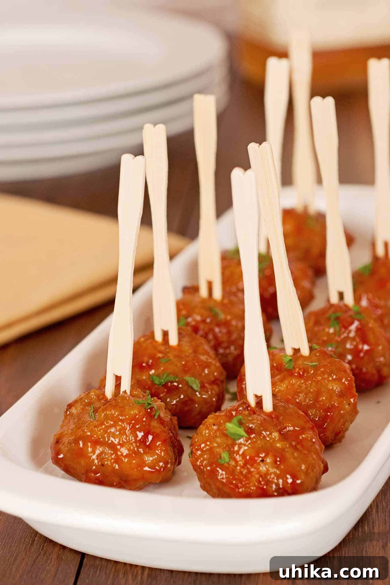 Whiskey Glazed Party Meatballs 2 Whiskey Glazed Cocktail Meatballs served in a white dish with wooden cocktail picks, garnished with chopped parsley. A perfect party appetizer.